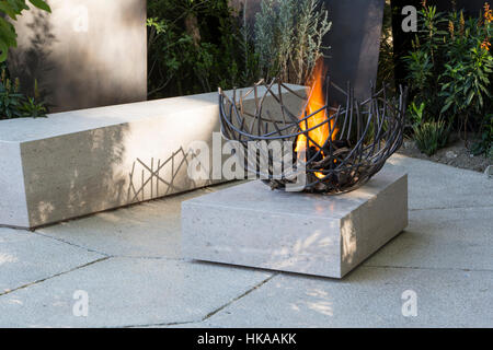 Auf der modernen Terrasse mit Steinbank und Feuerstelle im Freien befindet sich die Chelsea Flower Show London, der britische Designer Andy Sturgeon Stockfoto