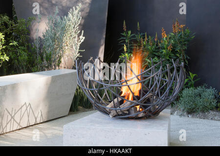 Eine moderne Steinterrasse mit Sitzbank und Feuerstelle im Freien The Telegraph Garden, Chelsea Flower Show 2016 London UK - Designer Andy Sturgeon Stockfoto