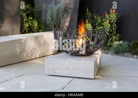 Eine moderne Steinterrasse mit Sitzbank und Feuerstelle im Freien The Telegraph Garden, Chelsea Flower Show 2016 London UK - Designer Andy Sturgeon Stockfoto