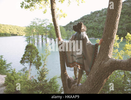 Junge Frau an einem Baum stehen und starrte auf den See. Stockfoto