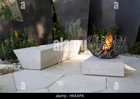 Eine moderne Steinterrasse mit Sitzbank und Feuerstelle im Freien The Telegraph Garden, Chelsea Flower Show 2016 London UK - Designer Andy Sturgeon Stockfoto