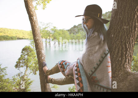 Junge Frau ruht auf einem Baum. Stockfoto