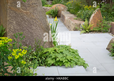 Steinpflasterter Gartenpfad in einem modernen Garten mit Steinblöcken für Hochbetten The M&G Garden, Cleve West, Chelsea Flower Show, London, Großbritannien Stockfoto