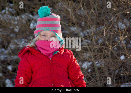 entzückende schulpflichtige Mädchen gebündelt in Hut und Winter Mantel draußen im Schnee Stockfoto