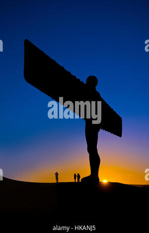 Angel of the North bei Sonnenuntergang. Menschen, die unter der Statue fotografiert. Dunkelblauen Himmel mit Sonne Einstellung Befing Engel. Stockfoto