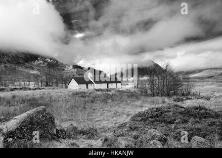 BlackRock Cottage, Glencoe mit stimmungsvoller Himmel in Monochrom. Stockfoto