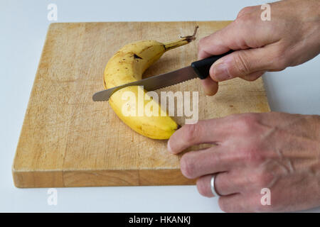 Schneiden eine Banane auf ein Schneidebrett Stockfoto