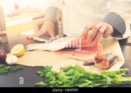 Chefkoch Lachs mit Kräutern und Gewürzen zum Kochen in der Küche Stockfoto