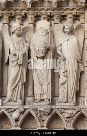 Saint-Denis (Dionysius) hält er den Kopf und von Engeln umgeben. Neo-gotische Statue an der Hauptfassade der Kathedrale Notre-Dame (Notre-Dame de Paris) in Paris, Frankreich. Beschädigte gotische Statuen an der Hauptfassade wurden in den 1840er Jahren von französischen Architekten Eugene Viollet-le-Duc und Jean-Baptiste Lassus restauriert. Stockfoto