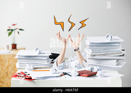 Die vielen zerknitterten Papiere auf Schreibtisch des gestressten Männern am Arbeitsplatz Stockfoto