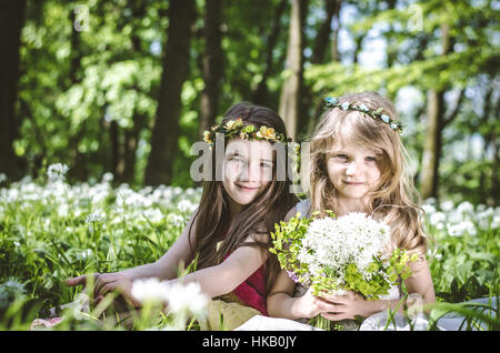 zwei schöne Freunde sitzen im grünen Frühlingswiese mit weißen Blüten im Wald Stockfoto