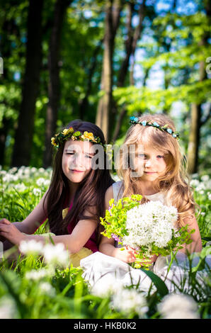 zwei schöne Freunde sitzen im grünen Frühlingswiese mit weißen Blüten im Wald Stockfoto