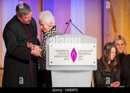 Cardiff, Wales, Großbritannien. 27. Januar 2017.  Holocaust-Überlebende Eva Clarke wird unterstützt durch The Reverend Canon Stewart Lisk nach der Lektüre ihrer Geschichte in den Dienst des Holocaust Memorial Day in Cardiff City Hall. Picture by Credit: Mark Hawkins/Alamy Live-Nachrichten Stockfoto