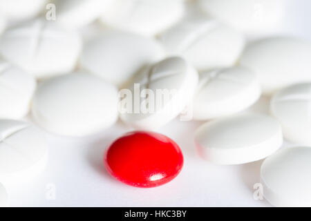 Eine rote Pille unter weißen Pillen medizinischen Hintergrund Konzept Stockfoto