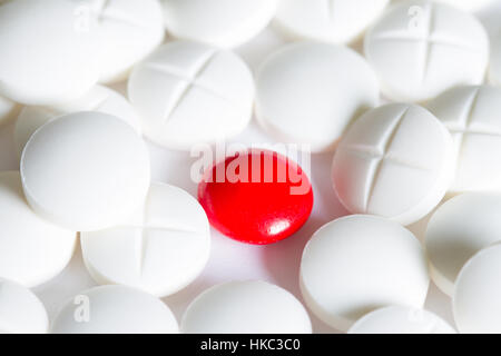 Eine rote Pille unter weißen Pillen medizinischen Hintergrund Konzept Stockfoto