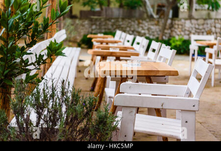 Caffe Bar oder ein Restaurant mit weißen Stühlen und Tischen. Nizza Platz zum Essen oder trinken in der Natur mit grünen Bäumen und Blättern. Stockfoto