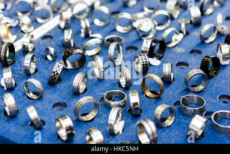 Zeigen Sie mit unterschiedlichen Designs handgefertigt Silber Ringe auf blauem Stand an. Nahaufnahme der handgemachten Schmuck Shop Schaufenster. Stockfoto