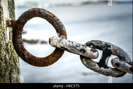 Alten rostigen Anker Schiff Eisenkette in Hafen am Meer. Alten Zaun aus veralteten Boot Kettenelemente mit Meer Ozean im Hintergrund. Stockfoto