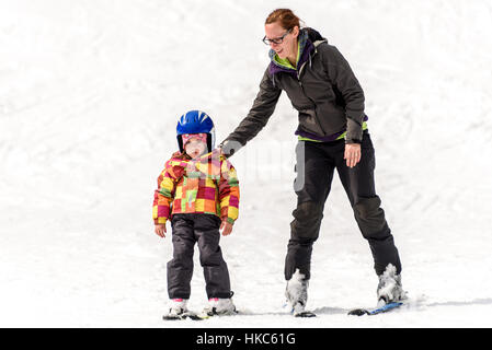 Professionelle Ski-Lehrer lehrt eine Kind an einem sonnigen Tag auf einem Hang Bergresort mit Sonne und Schnee Ski zu fahren. Familie und Kinder aktiv vacati Stockfoto