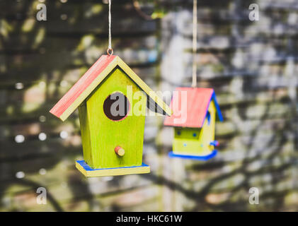 Zwei alte verwitterte DIY Vogelhäuschen an den Baum hängen. Bunte kleine Vogelhaus mit grünen Wänden. Stockfoto