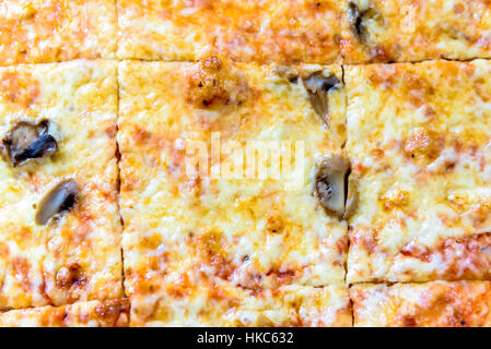 Quadratische Scheiben große Pizza zum mitnehmen. Vegetarische Pizza Margarita mit geschmolzenem Käse, Tomaten und Champignons geschnitten. Stockfoto