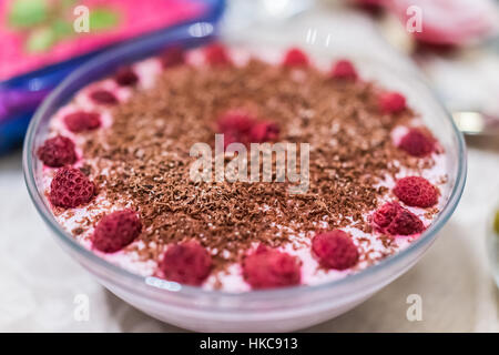 Himbeer-Käsekuchen im Glasschüssel mit Schokoraspeln verziert Stockfoto