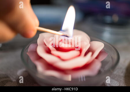 Hand-Beleuchtung rose Blume Kerze mit Gleichstock in Glasschüssel auf Tisch Stockfoto