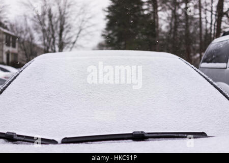 Schnee bedeckt die Windschutzscheibe am Auto mit Scheibenwischer Stockfoto