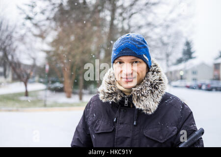 Porträt des Mannes in Mantel und blau Wintermütze im Winterschnee Stockfoto