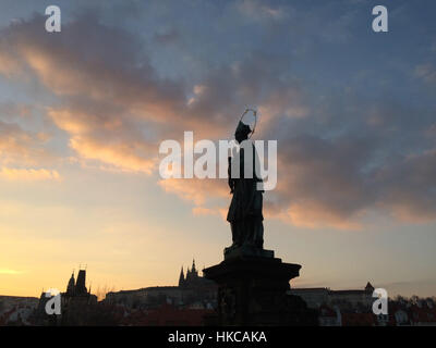 Statue des Heiligen Johannes von Nepomuk (Jan Nepomucky) auf der Karlsbrücke in Prag, Tschechische Republik, bei Sonnenuntergang. Stockfoto