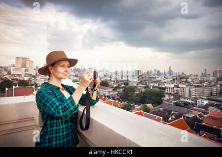 Touristischen Frau fotografieren mit Retro-Style-Kamera im Bangkok City Panorama mit Wolkenkratzern des Geschäftsviertels von Golden Mountain Wat Saket ro Stockfoto