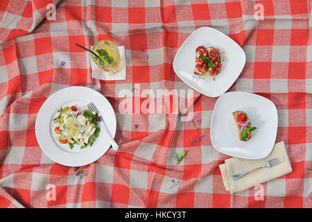 Picknick mit Sandwiches und Salat auf roten Quadraten material Stockfoto