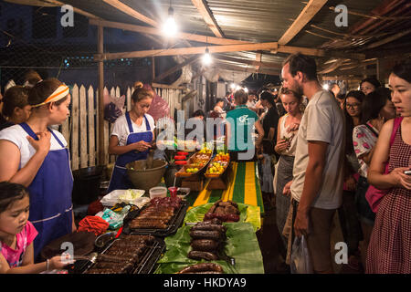 LUANG PRABANG, LAOS - 15. Mai 2015: Touristen kaufen Lebensmittel aus einem Marktstand in Luang Prabang Nachtmarkt. Stockfoto