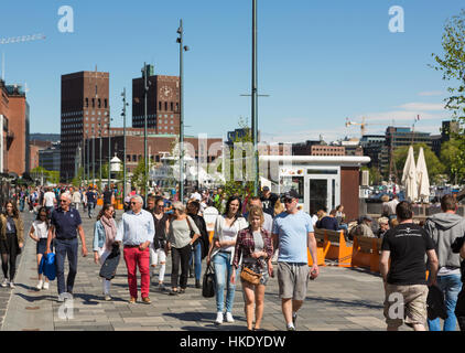 OSLO - 16. Mai 2016: Menschen, die einen Spaziergang entlang des renovierten Aker Brygge Hafens an einem sonnigen Tag in Norwegens Hauptstadt. Das Gebäude in der Hinterg Stockfoto