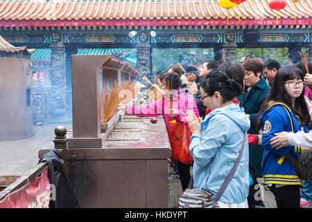 treu im Gebet mit Räucherstäbchen in Sik Sik Yuen Wong Tai Sin Tempel in Hong Kong Stockfoto