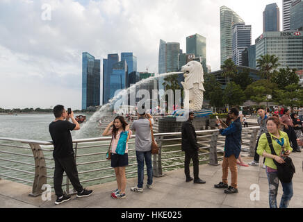 Singapur, Singapur - 22. Februar 2016: Touristen fotografieren vor der berühmten Skyline der Stadt und der Merlion Statue. Stockfoto