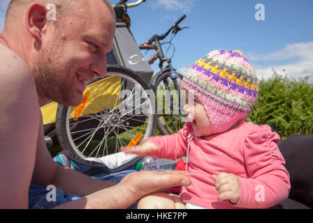 Mann und Baby im Sommer auf Fahrrädern in Schottland spielen im Freien. Stockfoto