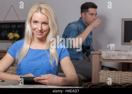 Blonde stolz Business-Frau sitzt mit Tablet im Acafeteria mit Kaffee und Wasser Stockfoto