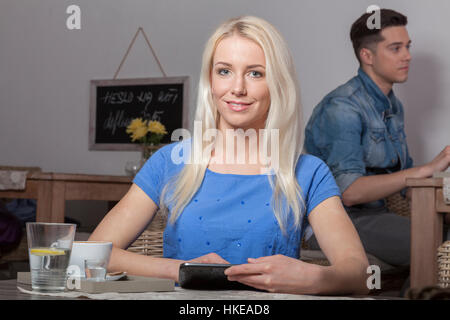 Blonde stolz Business-Frau sitzt mit Tablet im Acafeteria mit Kaffee und Wasser Stockfoto