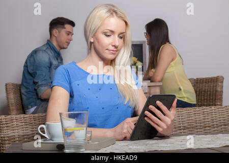 Blonden stolz Business-Frau sitzt mit Tablette in der Cafeteria mit Kaffee und Wasser Stockfoto
