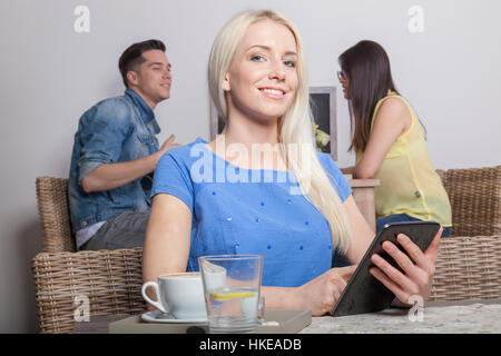 Blonde stolz Business-Frau sitzt mit Tablet im Acafeteria mit Kaffee und Wasser Stockfoto