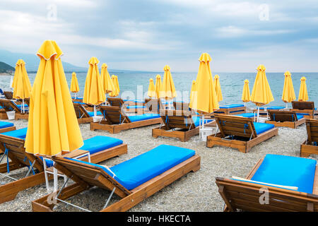 Sonnenschirme und leeren Liegestühlen an einem bewölkten Tag. Platamonas, Pieria, Mazedonien, Griechenland, Europa Stockfoto