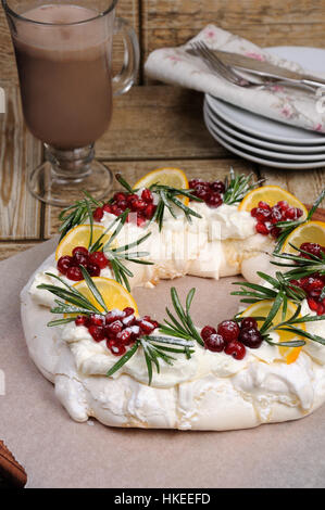 Pavlova Kuchen in der Form von ein Adventkranz der Meringue mit Rahm, Granatapfel, Cranberry, Rosmarin-Zweige Stockfoto