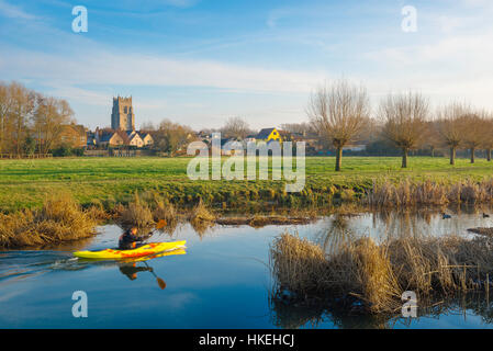 Ein Mann sein Gelbes Paddel Kanu auf dem Fluss Stour im Winter mit der Suffolk Stadt Sudbury im Hintergrund, Grieskirchen Bezirk, UK. Stockfoto