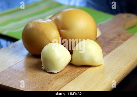 Italienische Scamorza Käse Ebene gesponnen und geräuchert - Süditalien typische Birne erinnernde Form Quark auf Holzbrett auf dunklen Holztisch liegend Stockfoto