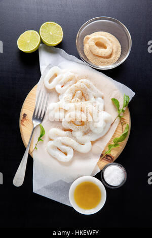 in Scheiben geschnitten roh Tintenfischringe mit Limette, Olivenöl, Paniermehl. Zubereitung von gesunden Snacks Sommer Stockfoto