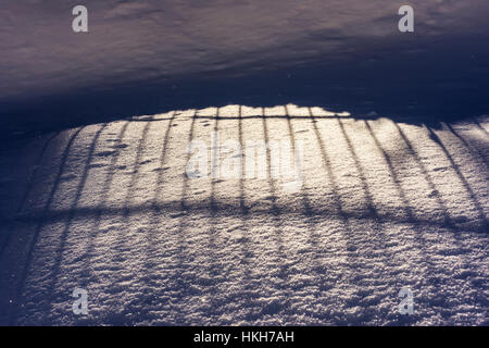 Abstrakte vertikale Schatten auf dem Schnee. Textur Hintergrund Winterkälte Tag hautnah. Stockfoto