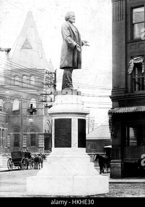 Ein Denkmal um zu Ehren von Frederick Douglass, eine Statue von Douglass steht auf einem Steinsockel, die mehrere Plaketten Text, Mauerwerk Gebäude, Straßen, enthält und Pferdekutschen sehen im Hintergrund, Douglass wurde einem entflohenen Sklaven, ein prominenter Abolitionisten wurde, er war bekannt für seine rednerischen Fähigkeiten und seine Unterstützung der gleichen Rechte für alle Menschen unabhängig von Rasse , Nationalität oder Geschlecht, diese Statue war das erste in den Vereinigten Staaten, eine Afrika-amerikanischer Staatsbürger, Rochester, New York, 1900 zu Ehren. Von der New York Public Library. Stockfoto