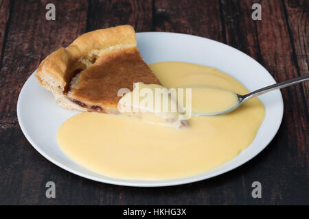 Ein Stück von Bakewell Pudding mit Vanillesauce Stockfoto