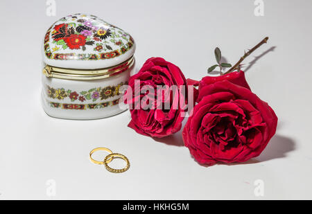 Romantische rote Rosen mit Verlobungsringen und kunstvollem Schmucketui für Valentinstag isoliert in weißem Hintergrund. Stockfoto